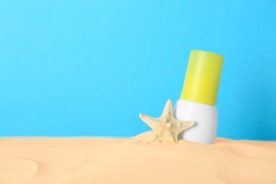Photo of Suntan product and starfish in sand against light blue background. Space for text