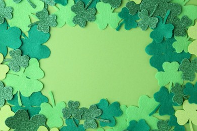 St. Patrick's day. Frame of decorative clover leaves on green background, top view. Space for text