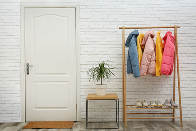 Wooden rack with stylish warm jackets in hallway