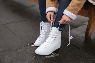 Photo of Woman lacing figure skate outdoors, closeup view