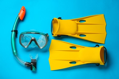 Pair of yellow flippers and mask on light blue background, flat lay