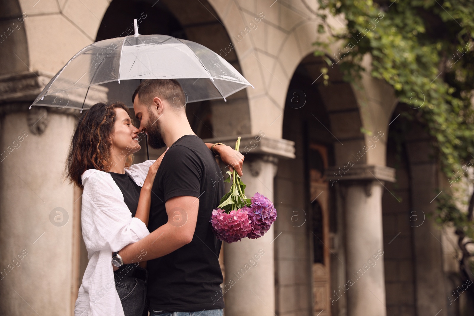 Photo of Young couple with umbrella enjoying time together under rain on city street