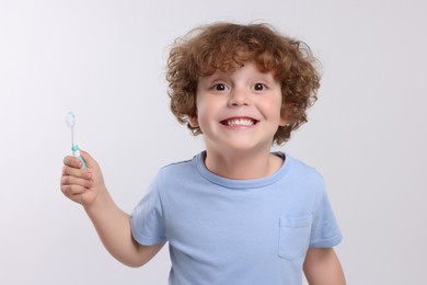 Photo of Cute little boy holding plastic toothbrush on white background