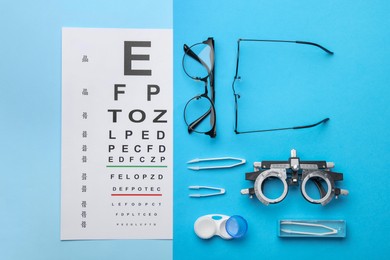 Flat lay composition with vision test chart and glasses on light blue background