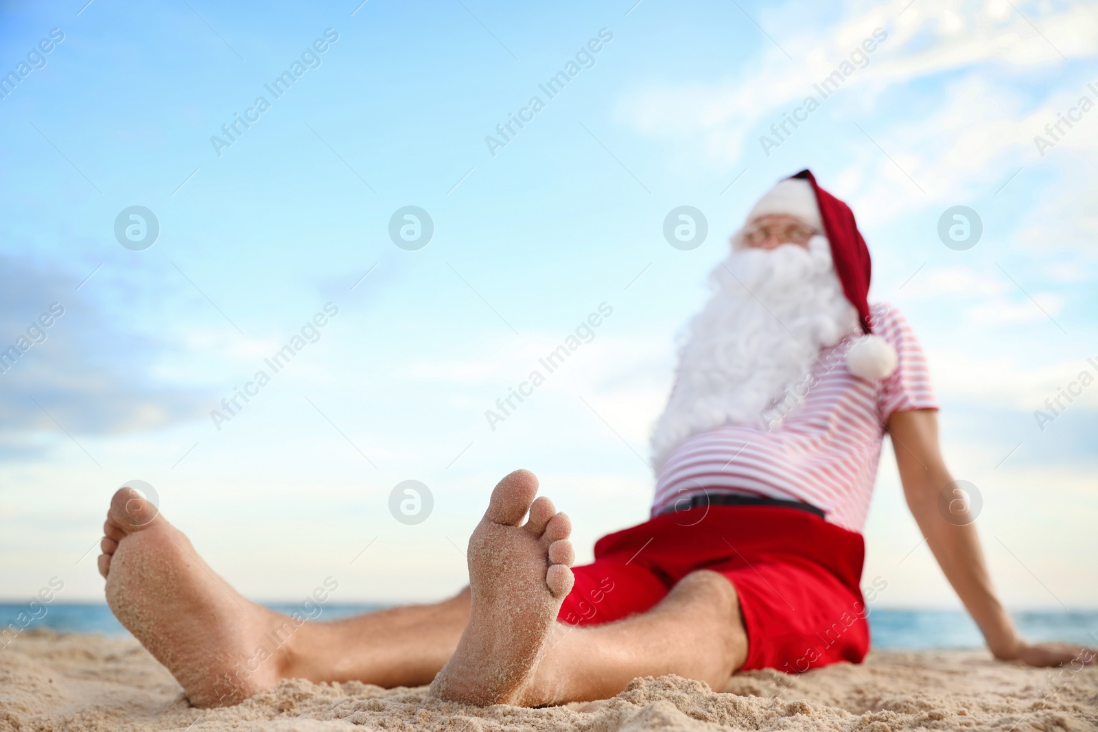 Photo of Santa Claus relaxing on beach, space for text. Christmas vacation