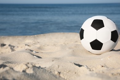 Soccer ball on beach, space for text. Football equipment