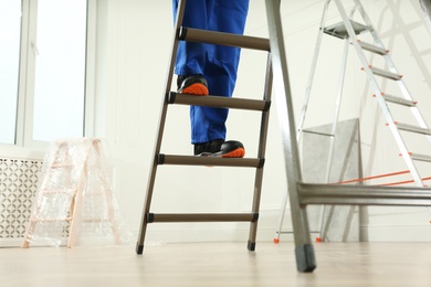 Photo of Professional worker climbing up ladder indoors, closeup