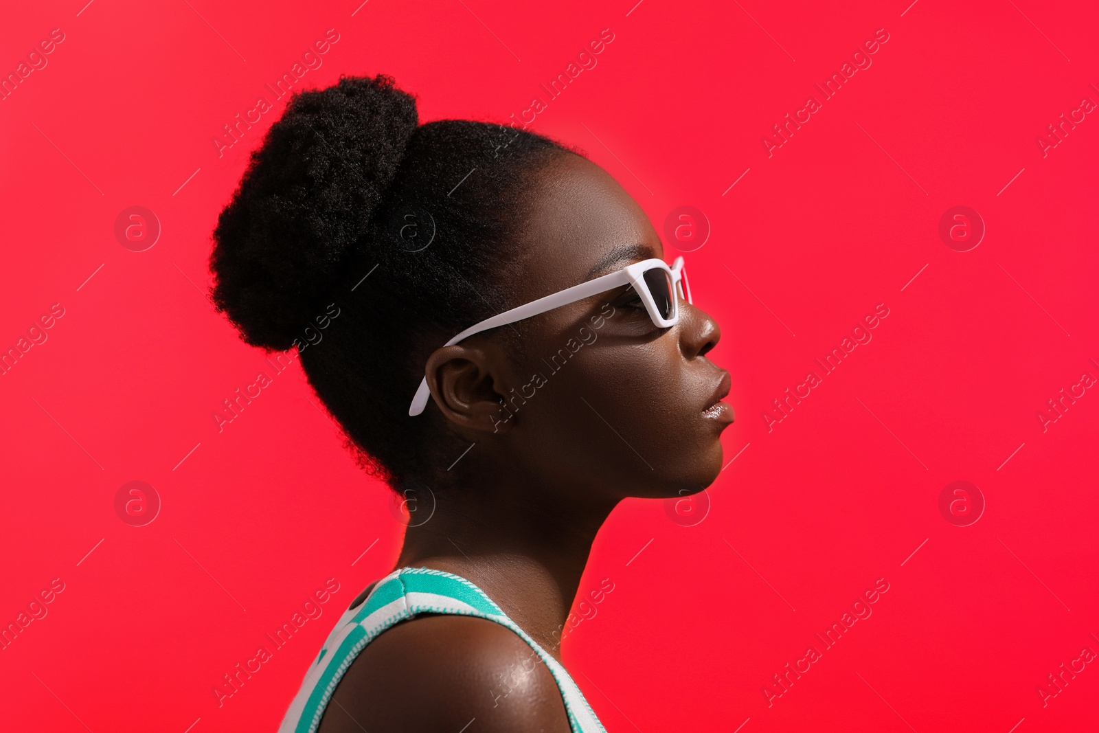 Photo of Fashionable portrait of beautiful woman with stylish sunglasses on coral background