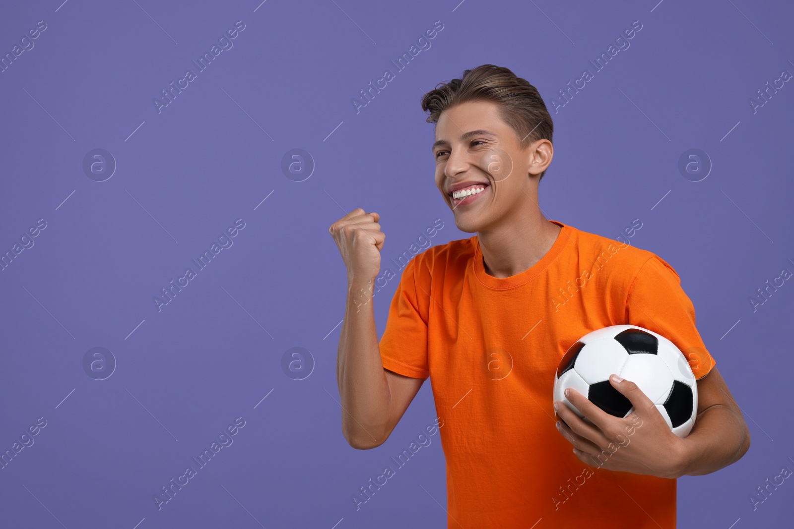 Photo of Happy sports fan with soccer ball on purple background. Space for text