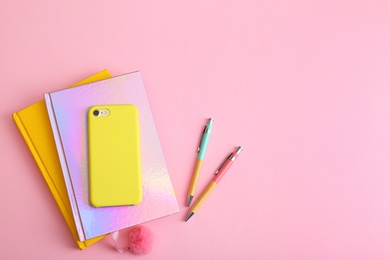 Photo of Smartphone, notebooks and pens on pink background, flat lay