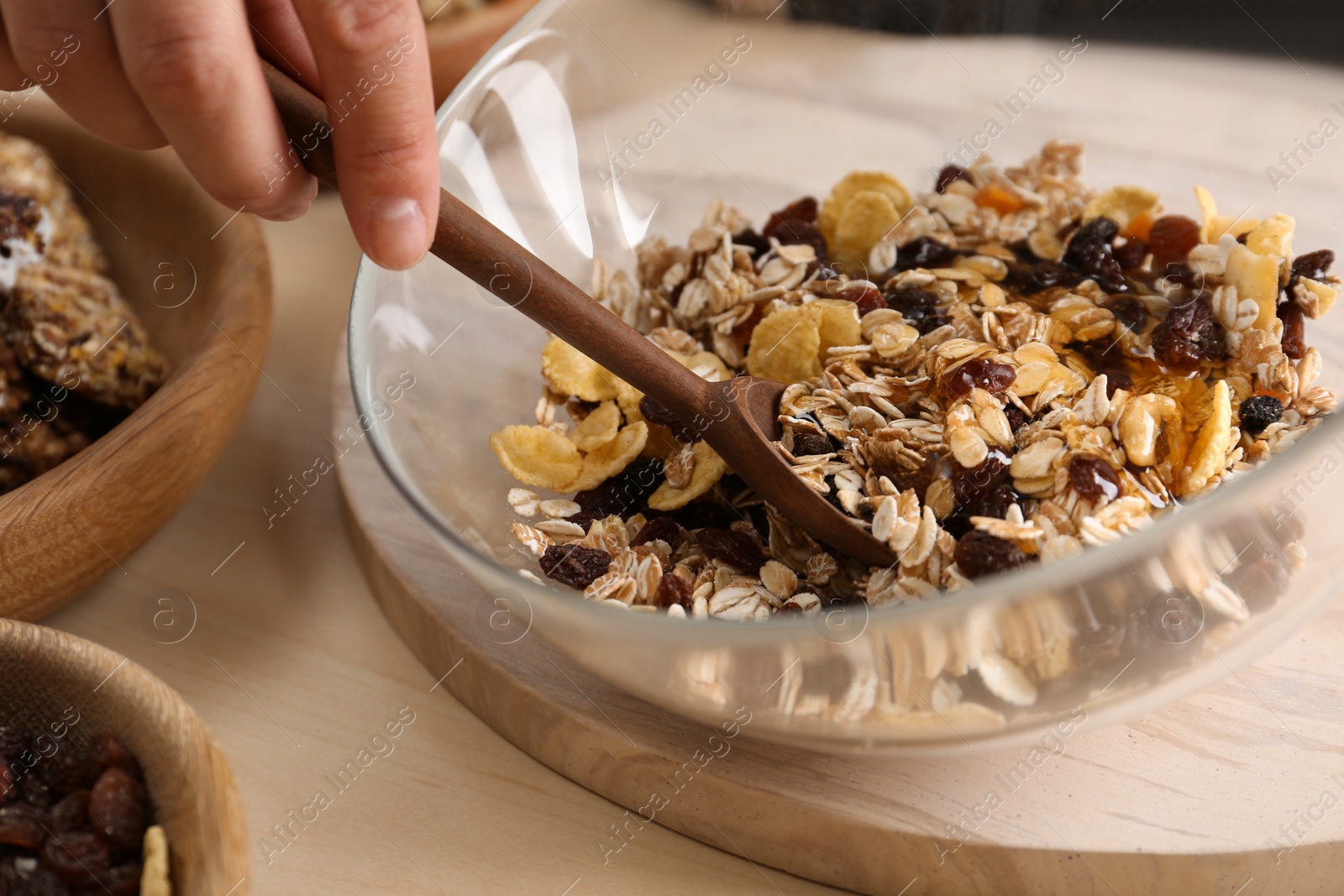 Photo of Woman preparing healthy granola bar at wooden table, closeup