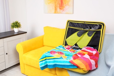 Packed suitcase for summer vacation on sofa in living room