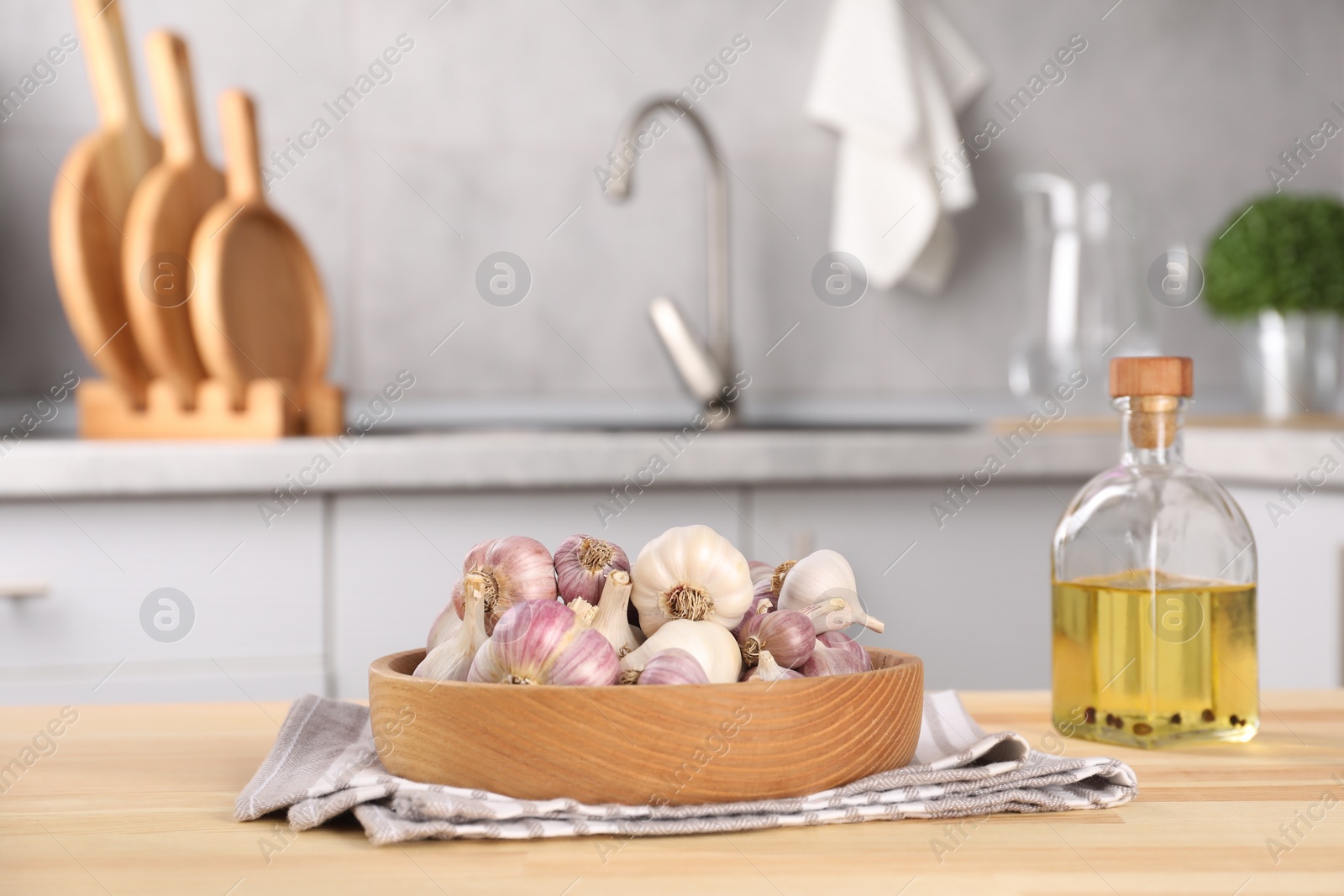 Photo of Bowl of fresh raw garlic and oil on wooden table in kitchen