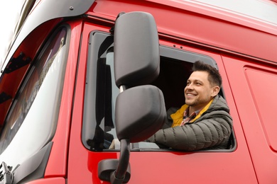 Photo of Portrait of happy driver in cab of modern truck