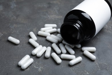 Photo of Amino acid pills and jar on grey table, closeup