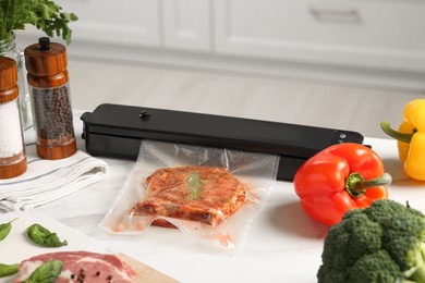 Photo of Sealer for vacuum packing with meat in plastic bag on white kitchen table