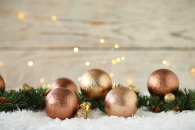 Photo of Beautiful Christmas balls and fir branches on snow against blurred festive lights. Space for text