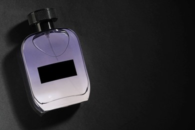Photo of Luxury men`s perfume in bottle on black background, top view. Space for text