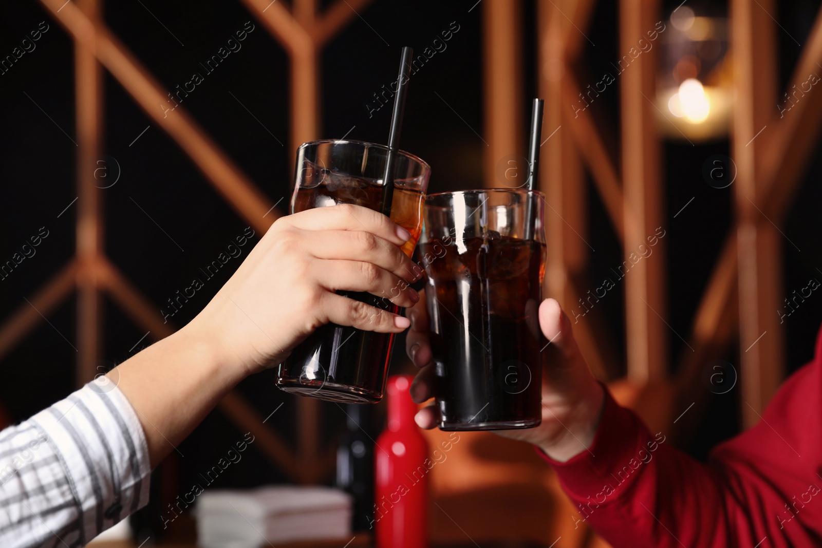 Photo of Young couple with glasses of refreshing cola indoors, closeup