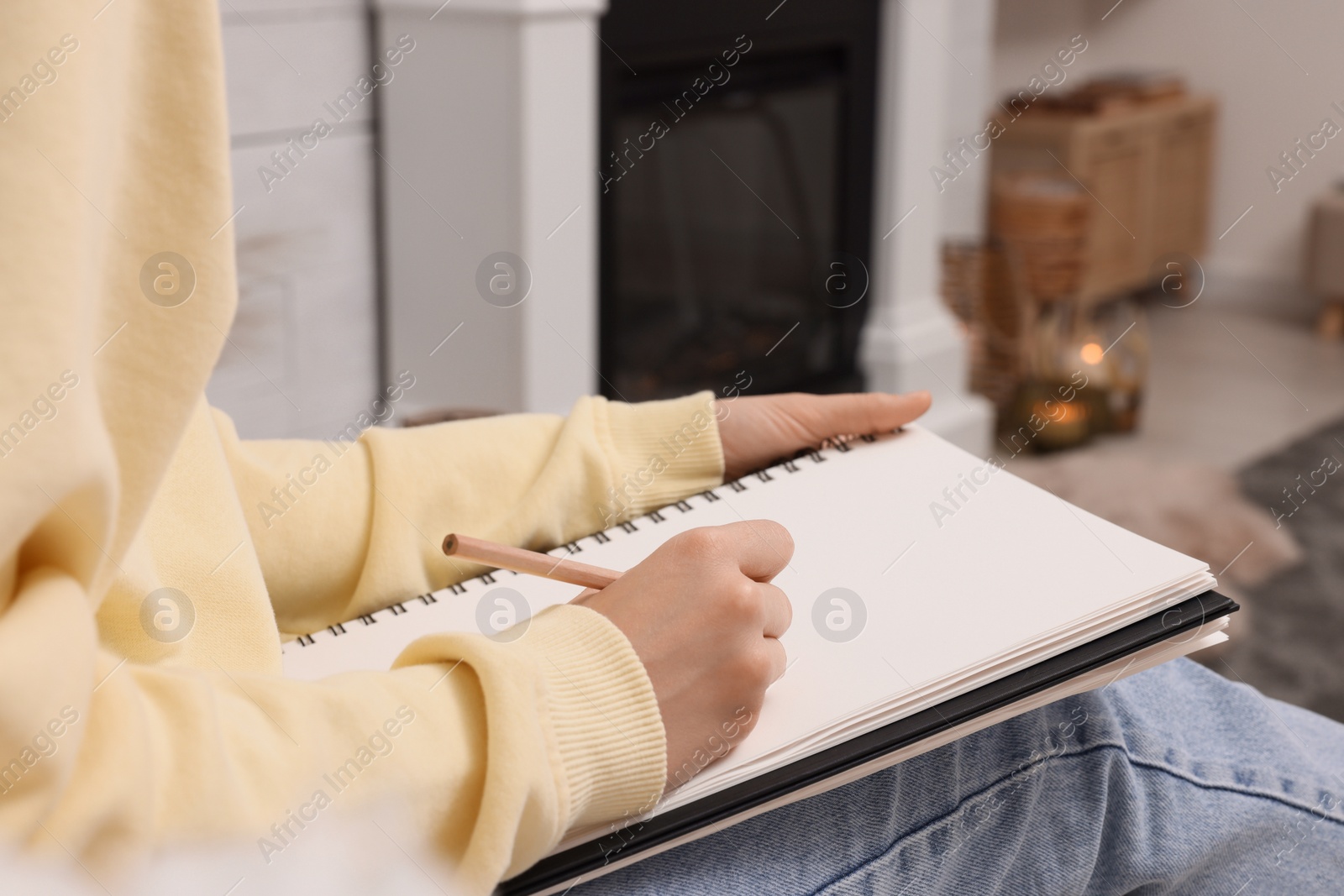 Photo of Young woman drawing in sketchbook at home, closeup