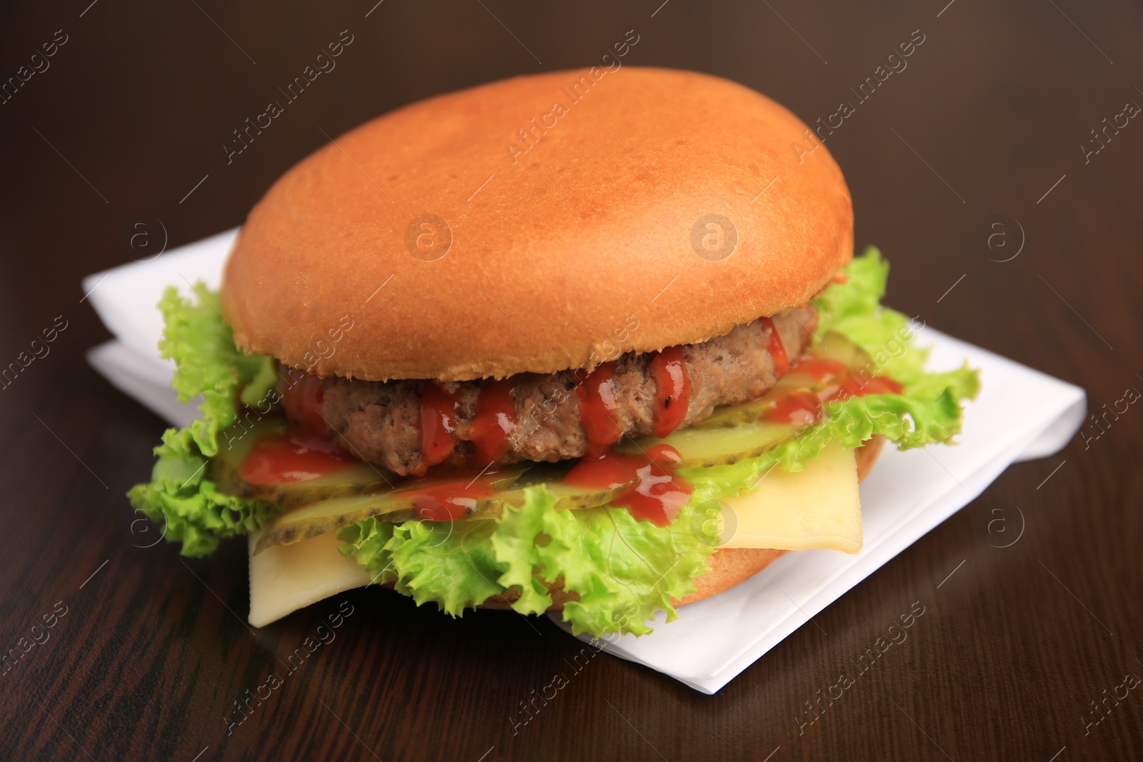 Photo of One tasty burger with patty, lettuce and cheese on wooden table, closeup