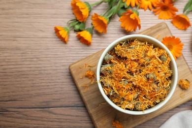 Photo of Dry and fresh calendula flowers on wooden table, flat lay. Space for text