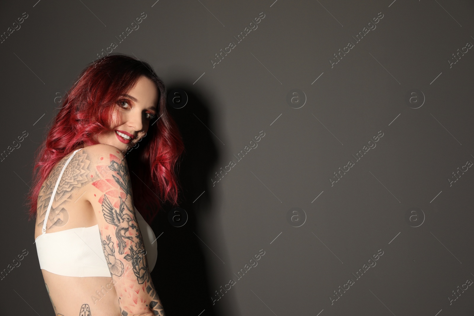 Photo of Beautiful woman with tattoos on body against black background. Space for text