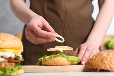 Woman making delicious vegetarian burger at table, closeup