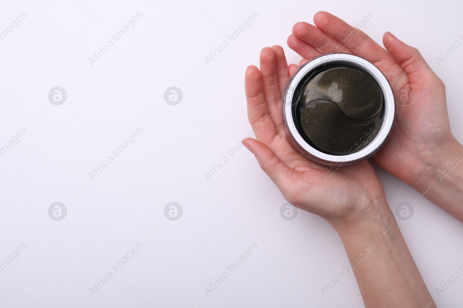 Photo of Woman holding jar with under eye patches on white background, top view. Cosmetic product