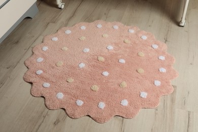 Photo of Round pink rug with polka dot pattern on wooden floor in room