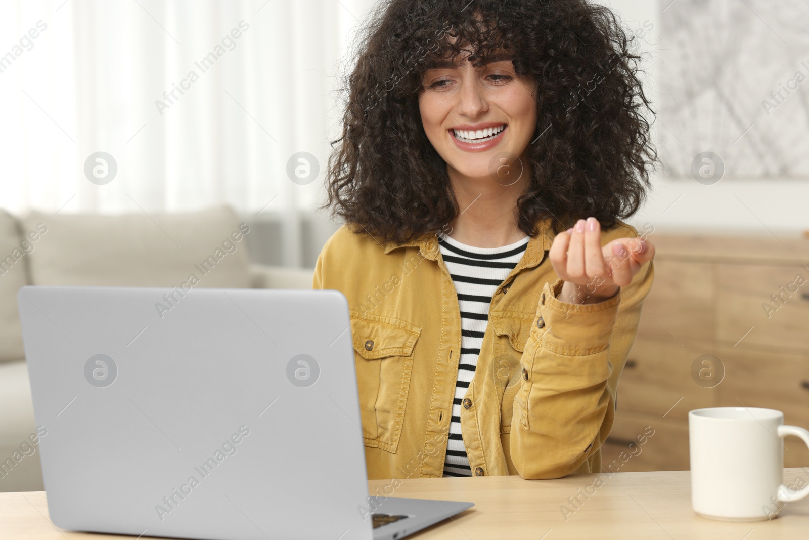 Photo of Happy woman having video chat via laptop at table in room