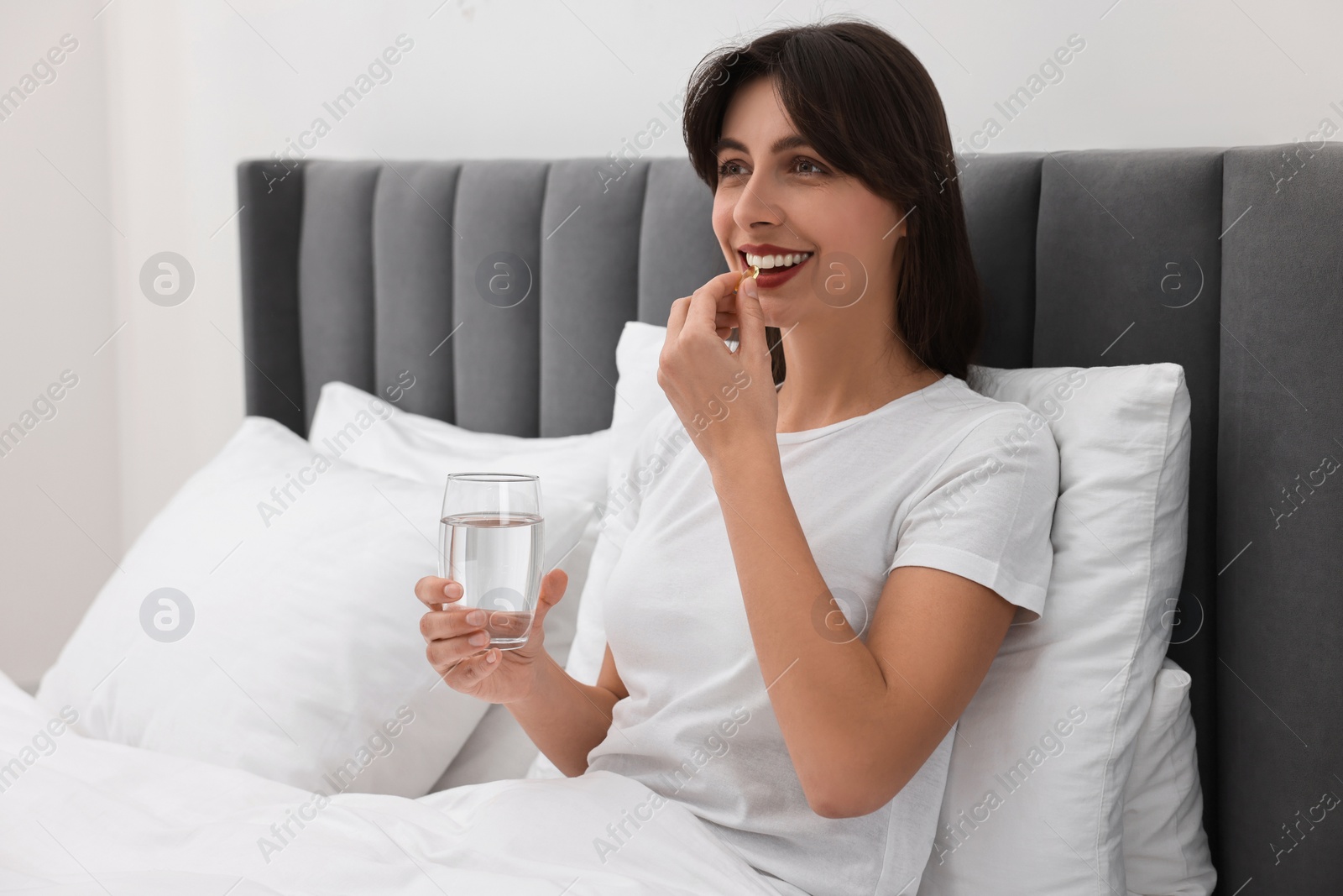 Photo of Beautiful woman taking vitamin pill at home