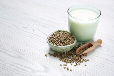 Hemp seeds and glass of milk on wooden background