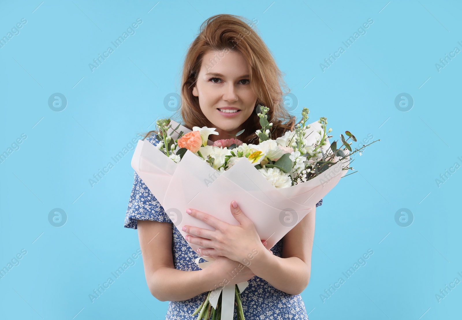 Photo of Beautiful woman with bouquet of flowers on light blue background