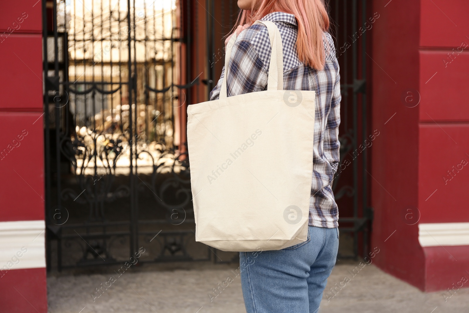 Photo of Young woman with cotton bag on city street, closeup. Mockup for design