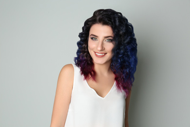 Young woman with bright dyed hair on light background