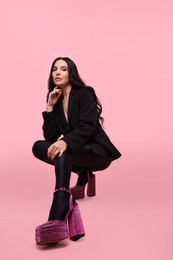 Stylish woman in black jacket on pink background