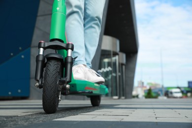 Photo of Man riding modern electric kick scooter on city street, closeup. Space for text