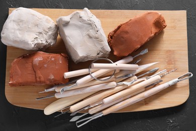 Clay and set of modeling tools on black table, top view