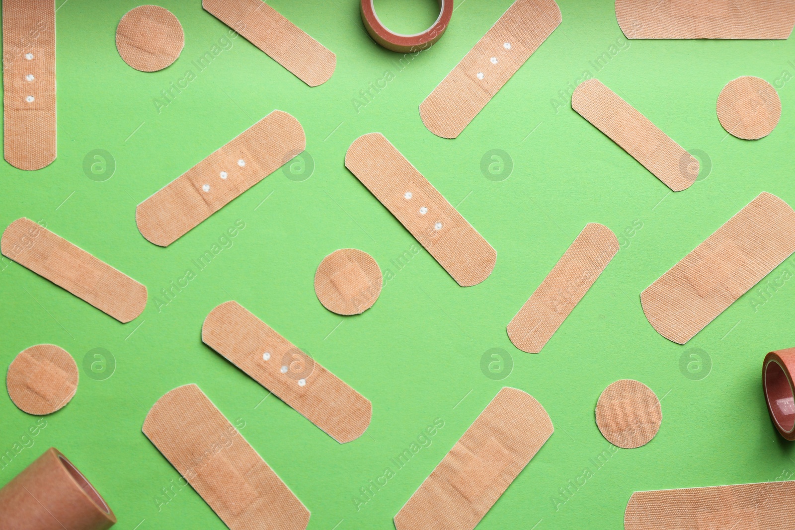 Photo of Different types of sticking plasters on green background, flat lay