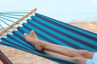 Photo of Young woman resting in comfortable hammock at seaside