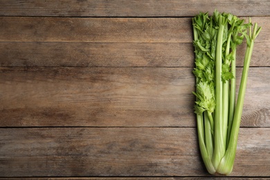 Photo of Fresh green celery on wooden table, top view. Space for text