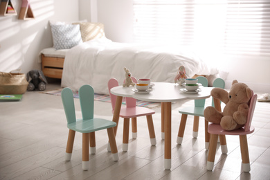 Small table and chairs with bunny ears in children's room interior