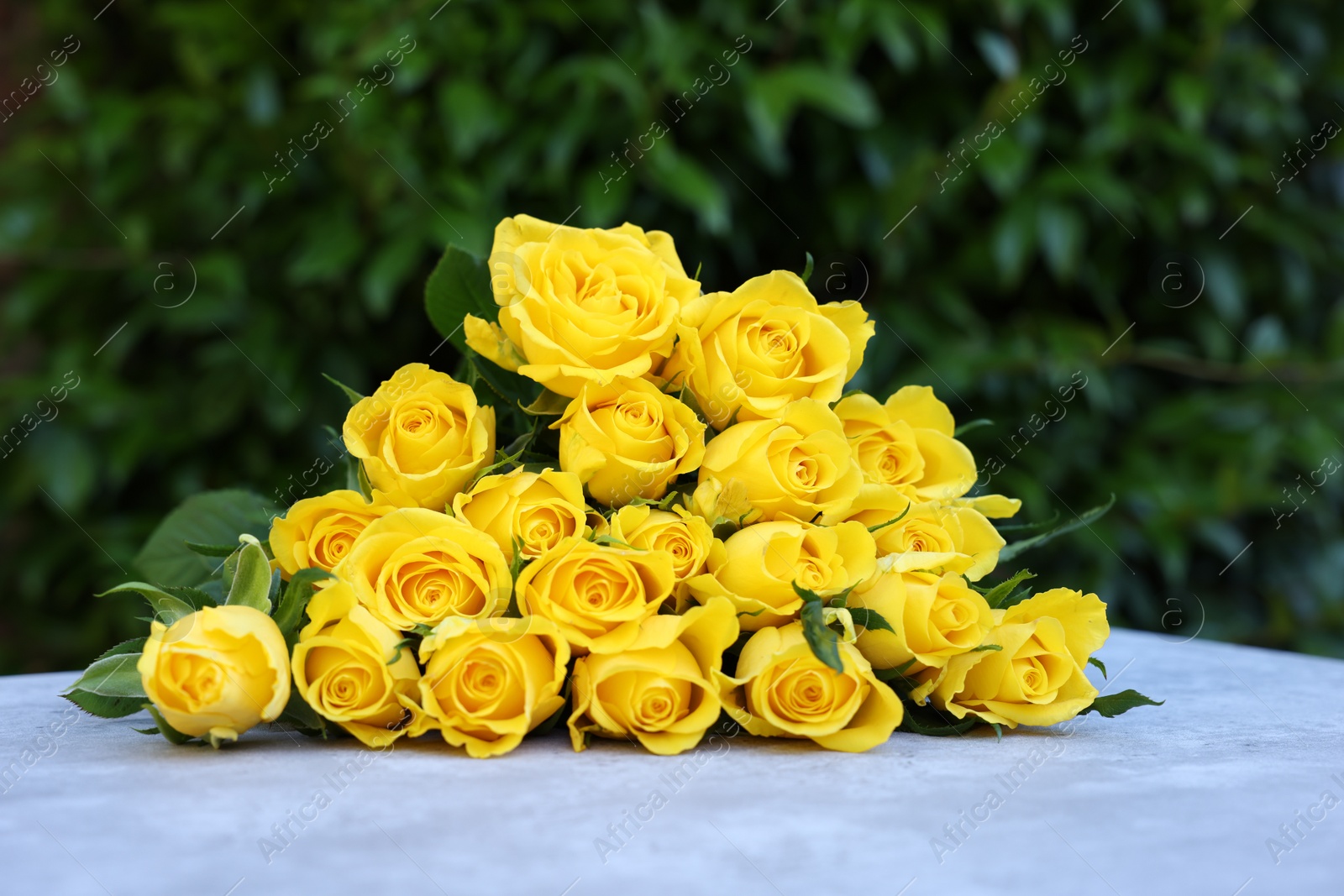 Photo of Beautiful bouquet of yellow roses on light table outdoors