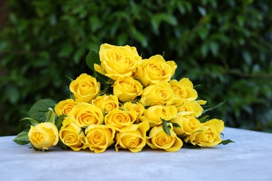 Photo of Beautiful bouquet of yellow roses on light table outdoors