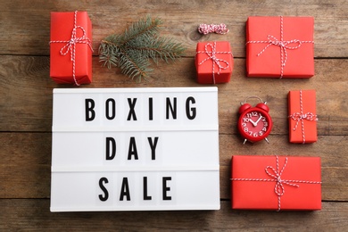 Flat lay composition with Boxing Day Sale sign and Christmas gifts on wooden table