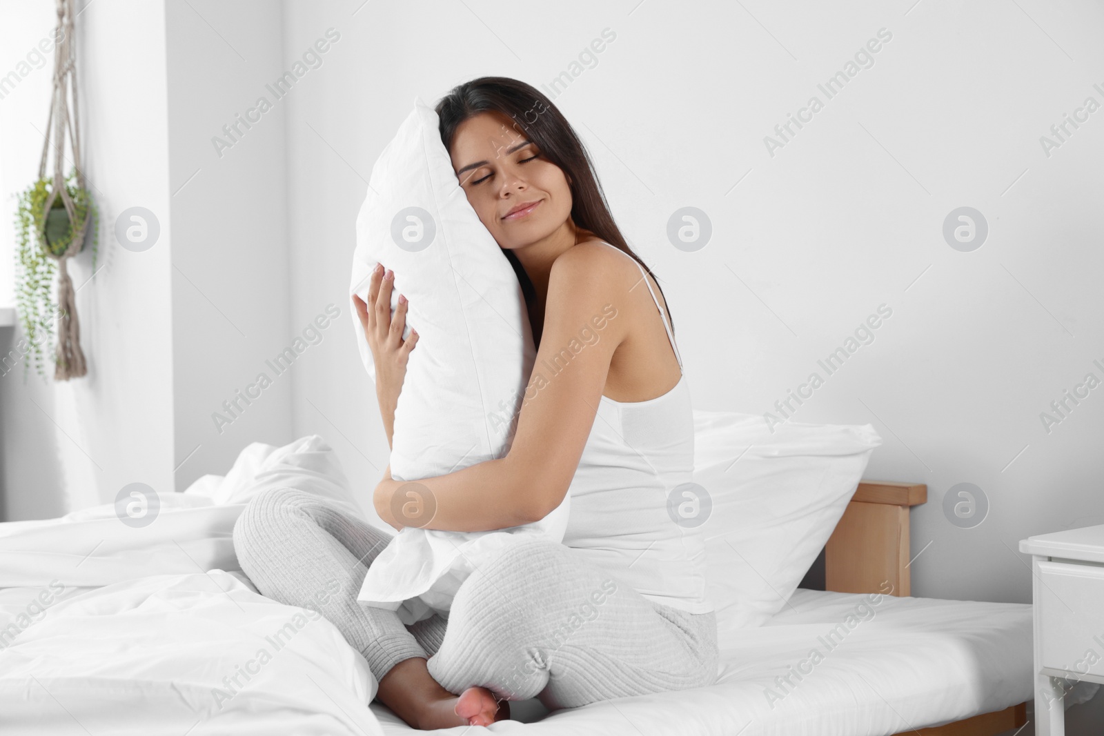 Photo of Beautiful young woman hugging pillow on bed at home