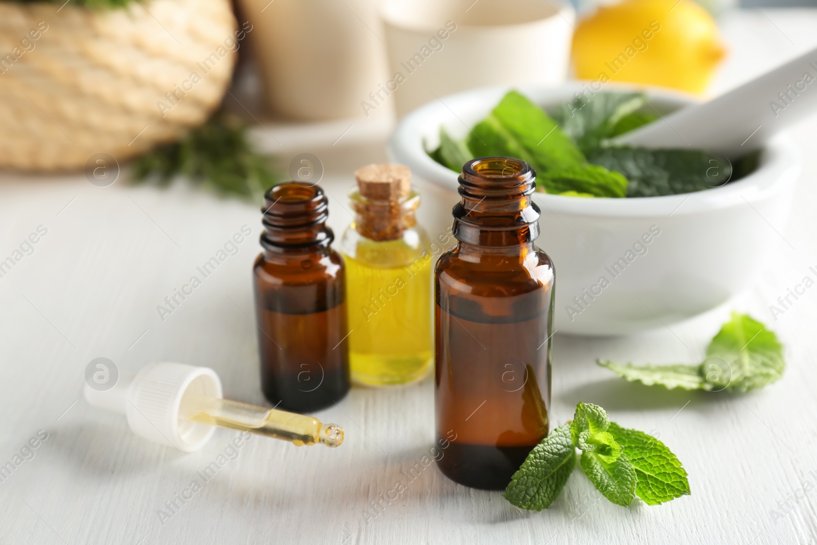 Photo of Bottles with mint essential oil on white wooden table