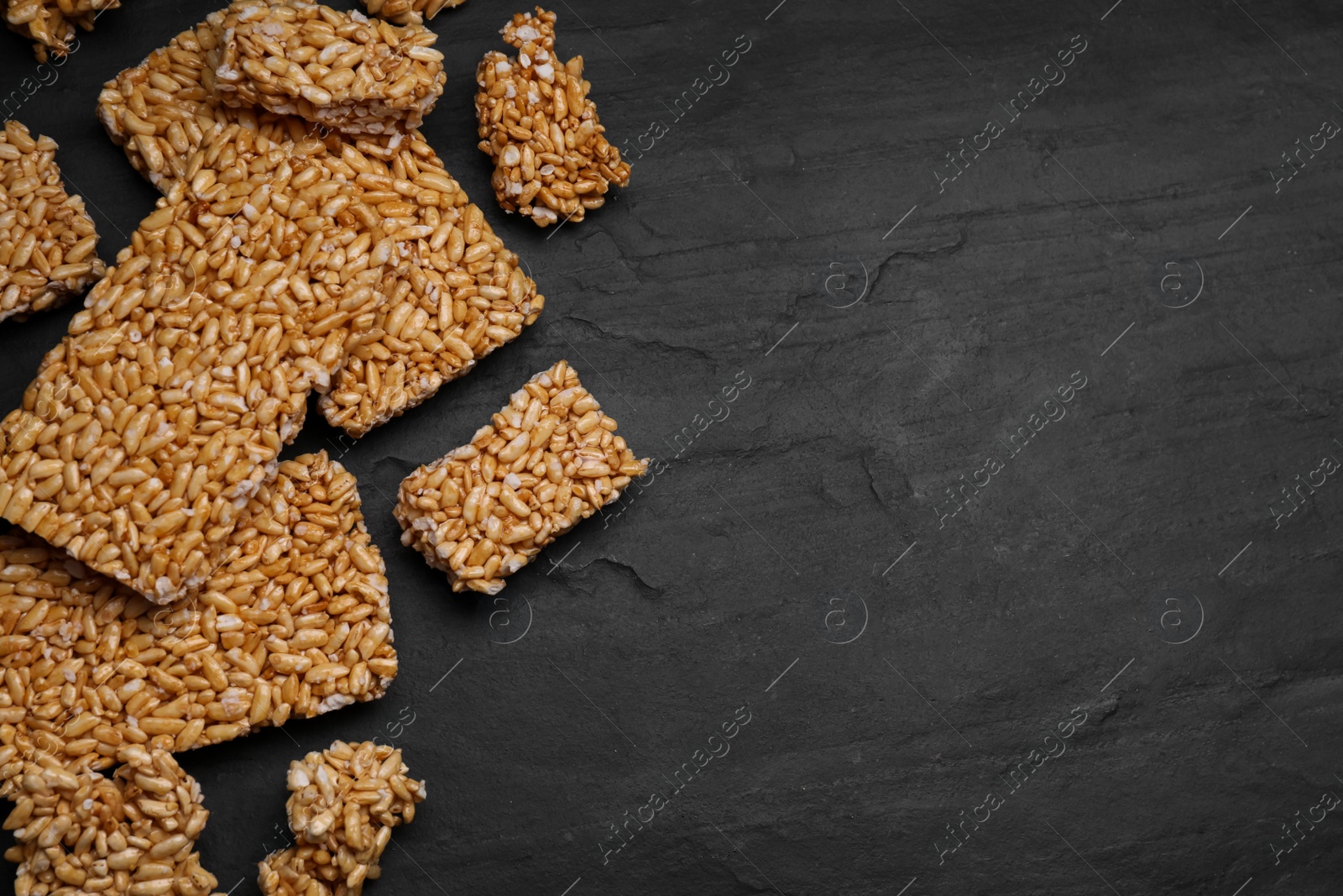Photo of Puffed rice bars (kozinaki) on black table, flat lay. Space for text