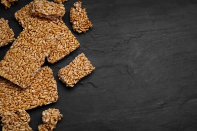 Photo of Puffed rice bars (kozinaki) on black table, flat lay. Space for text